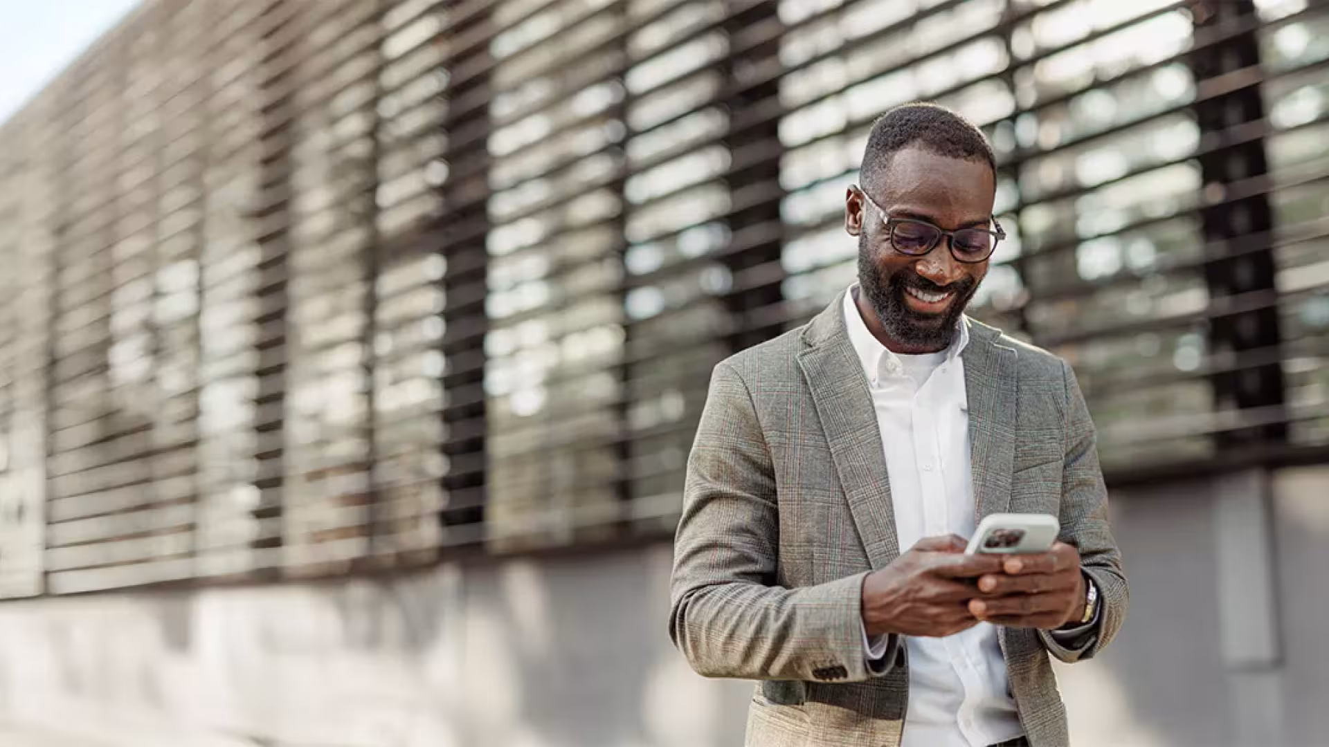 Homme marchant dans la rue en consultant son téléphone